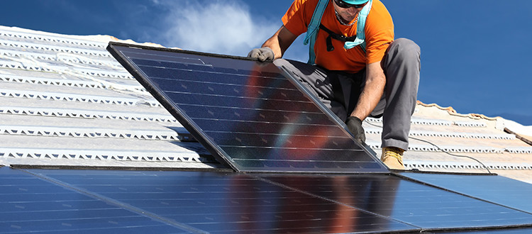Man installing large solar panels on a roof